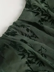 Gros plan sur le tissu en tulle transparent vert avec motif papillon floqué vintage.