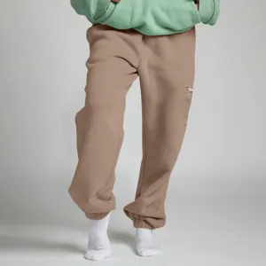 Vista di dettaglio dei pantaloni sportivi in felpa kaki con orli a costine e tasca con zip laterale.