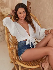 Detailaufnahme der eleganten weißen Strandüberwurf-Bluse mit Bindeborte und kurzen Jeans.