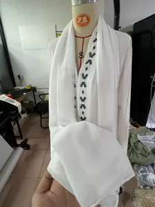 White long robe dress set with black geometric embroidery, long sleeves and scarf.