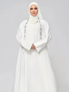 White abaya dress detail featuring elegant black and white geometric embroidery trims.