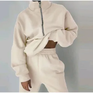 Close-up detailed shot of beige fleece half-zip sweatshirt and sweatpants activewear set.