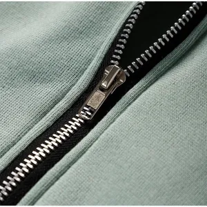 Detailed view of the metal zipper and soft fleece fabric of a casual green hoodie.