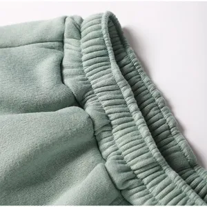 Detailed shot of the elastic waistband on soft sage green fleece sweatpants for daily casual wear.