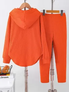 Orange pleated two-piece lounge set detail, showing the textured fabric, hoodie, and long pants.