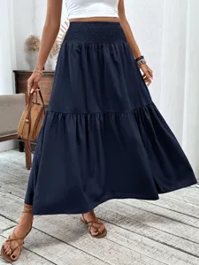 Detail view of solid dark blue tiered maxi skirt with high smocked waist and elegant drape.