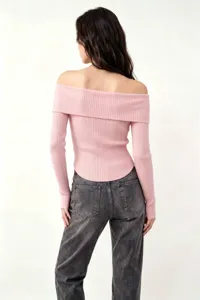 Vista posteriore di un maglione a coste rosa con spalle scoperte e jeans grigi.
