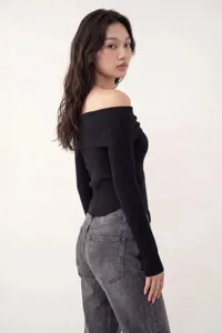 Dettaglio dell'elegante top nero con spalle scoperte in maglia a coste, maniche lunghe.
