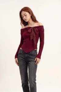Dettaglio in primo piano del top in maglia a costine bordeaux con fiocco trasparente.