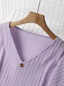 Close-up of a light purple V-neck knitted sweater detail, showing soft vertical ribbed texture.