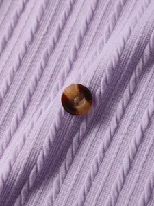 Close-up detail of a stylish purple vertical ribbed knit sweater with a tortoiseshell button.