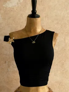 Top corto nero monospalla da donna con elegante spilla dorata e vestibilità aderente.
