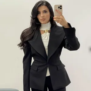 Women's gold ring halter sleeveless top paired with chic black blazer for stylish spring look.