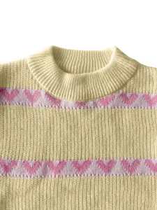 Close up detail of a cute women's cream knit sweater with pink heart pattern and round collar.