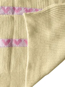 Close-up detail of soft knit sweater fabric featuring light yellow texture and cute pink hearts.