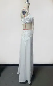 White two-piece beach cover-up set with elegant lace details, crop top and long skirt design.