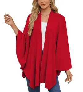 Close-up detail of the elegant solid red knit poncho cape cardigan, soft fabric texture.