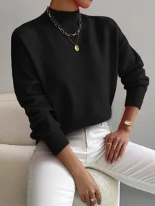 Primo piano dettagliato di un elegante maglione nero a collo alto da donna in ambiente moderno.