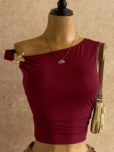 Dettagli del top corto asimmetrico ed elegante in rosso vino con decorazione di stella marina.