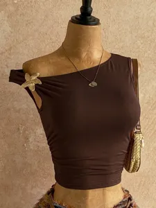 Dettagli del top corto asimmetrico marrone con elegante dettaglio floreale dorato e alla moda.