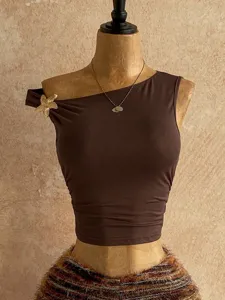 Dettagli del crop top marrone monospalla con un elegante dettaglio di stella marina dorata.