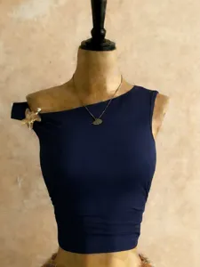 Dettaglio top corto monospalla blu scuro, capo estivo aderente con elemento decorativo metallico.