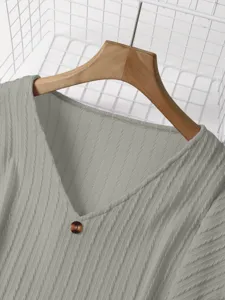 Closeup detail of the soft grey V-neck knitted sweater showing ribbed texture and a front button.