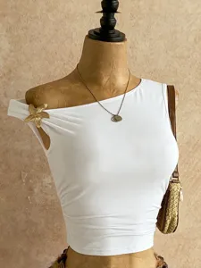 Elegante crop top bianco asimmetrico con fiore in metallo, streetwear estivo trendy.