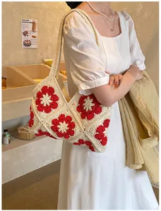 Detailaufnahme einer handgefertigten Häkeltasche mit rotem Blumenmuster und Textur.