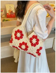 Handgefertigte Häkeltasche mit roten floralen Quadraten in einer Lifestyle-Umgebung.