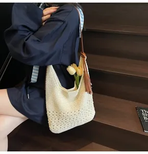 Primer plano de bolso bombonera tejido con calado floral y borla de cuero marron