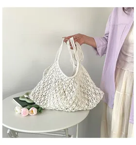Detailed view of hand-woven white hollow-out tote bag held by a model