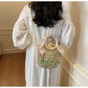 Detailed view of summer straw bucket bag with green hello lettering and floral scarf