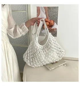 Detailed view of white woven macramé tote bag with intricate mesh pattern and interior pouch.