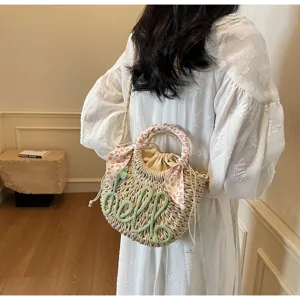 Back view of woman carrying a summer straw bucket bag with 'hello' embroidery and floral scarf