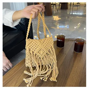Detailed view of a handmade macrame tassel bag with woven patterns in a cafe setting