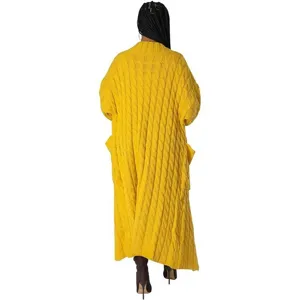 Lange gele kabelgebreide vest detail met comfortabele oversized pasvorm en zakken.