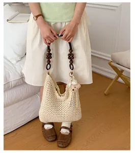 A detailed view of a cream hollow woven tote bag featuring a unique wooden bead handle