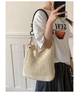 Detail of beige crochet woven tote bag with wooden bead strap and cute bear charm