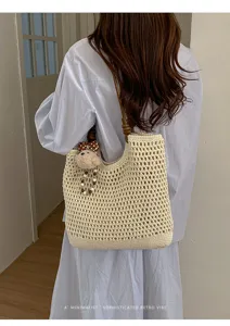 Donna che indossa una borsa tote traforata beige con ciondolo a forma di orso