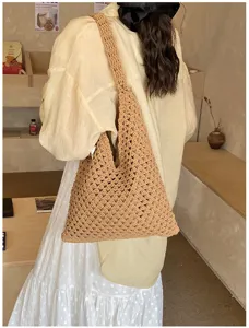 Back view of model wearing a beige handmade crochet beach tote bag in a cafe setting