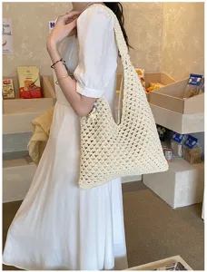 Detailed view of an off-white hand-crocheted hollow tote bag on a woman's shoulder