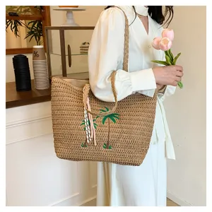 Fashionable woven straw tote bag featuring palm tree embroidery and elegant tassels.