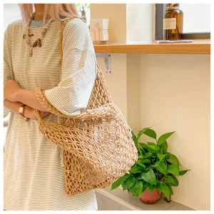 Detail view of a beige woven cotton rope tote bag with drawstring inner lining worn by a model.