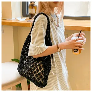Handmade black woven rope tote bag with drawstring lining worn by a model in a cafe