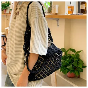 Black cotton rope hollow-out woven tote bag shown in a stylish lifestyle café setting