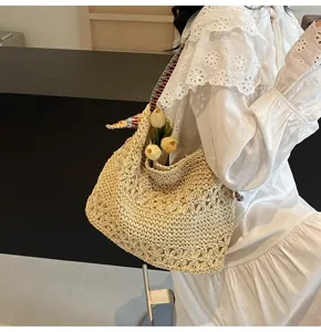 Detailansicht der Strohtasche mit floralem Lochmuster und buntem Schultergurt.