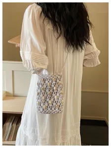 Handmade woven macramé crossbody phone bag with wooden beads on model in white dress