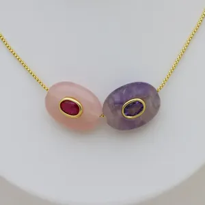 Nahaufnahme der luxuriösen Doppelstein-Anhängerhalskette mit goldener Kette und Zirkonen.