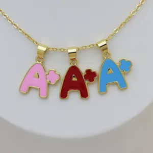Primer plano del collar con colgante de letra A+ de colores y detalles de esmalte brillante.